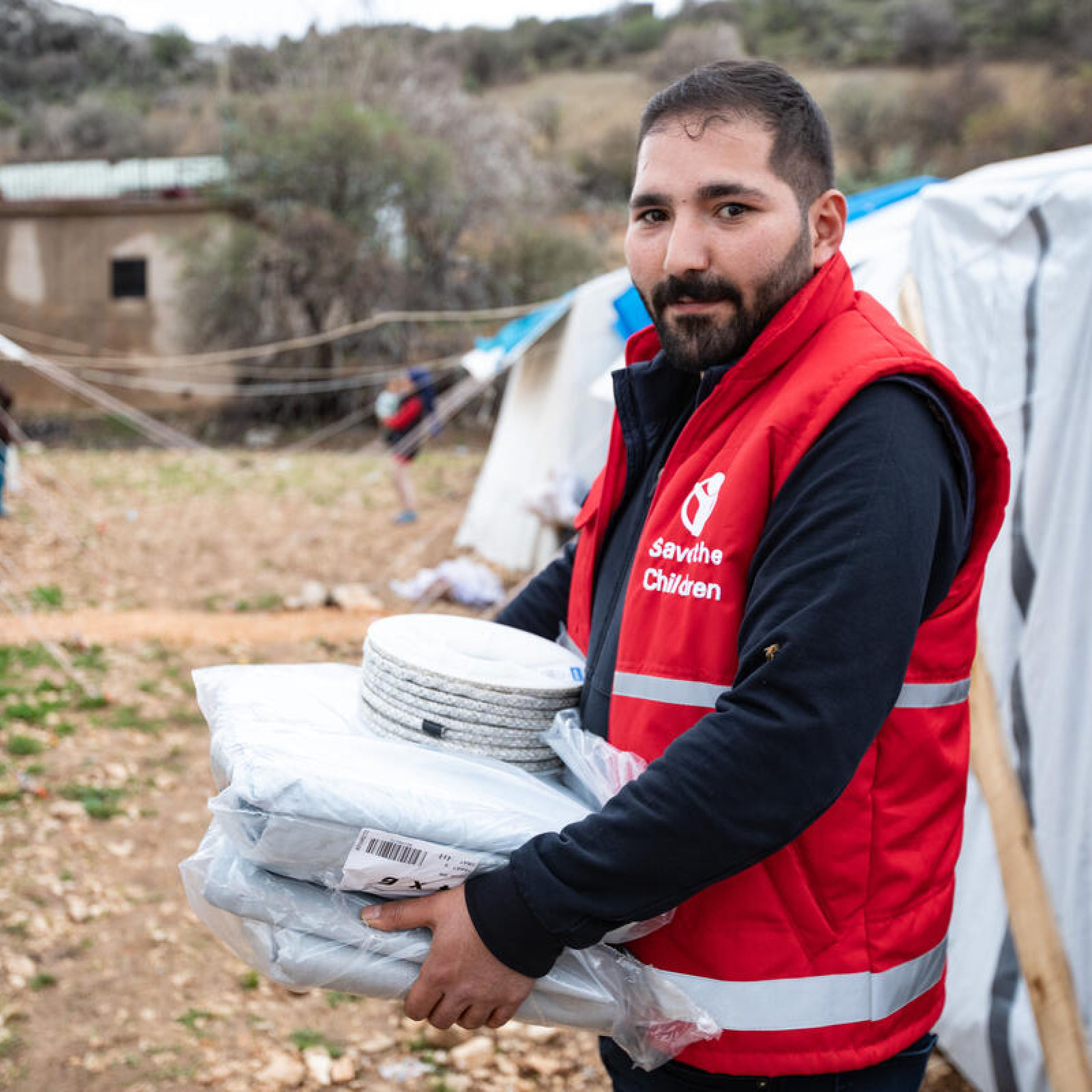 Burak, Save the Children staff member, distributes tarpaulins and rope in a village in the earthquake-hit region of Adiyaman