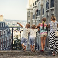 Mother and kids visiting Paris. They are watiching beautiful Paris view from the top of Montmartre. One of the boys is pointing at something.